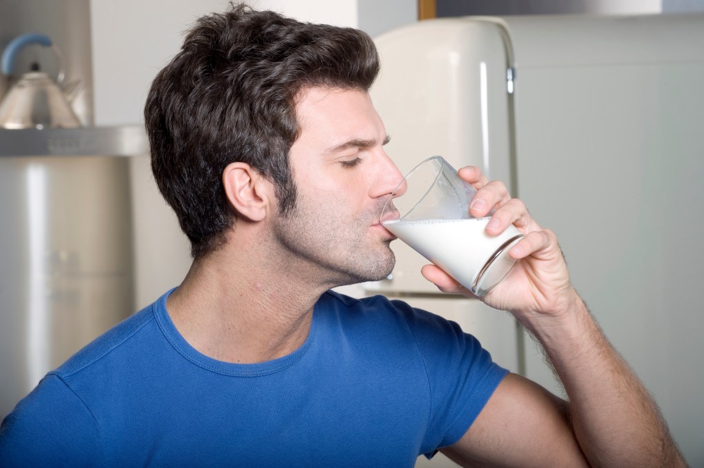 A man drinks a glass of milk.